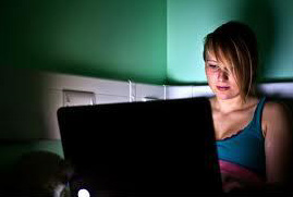 girl on computer when she should be sleeping resulting in sleep deprivation.